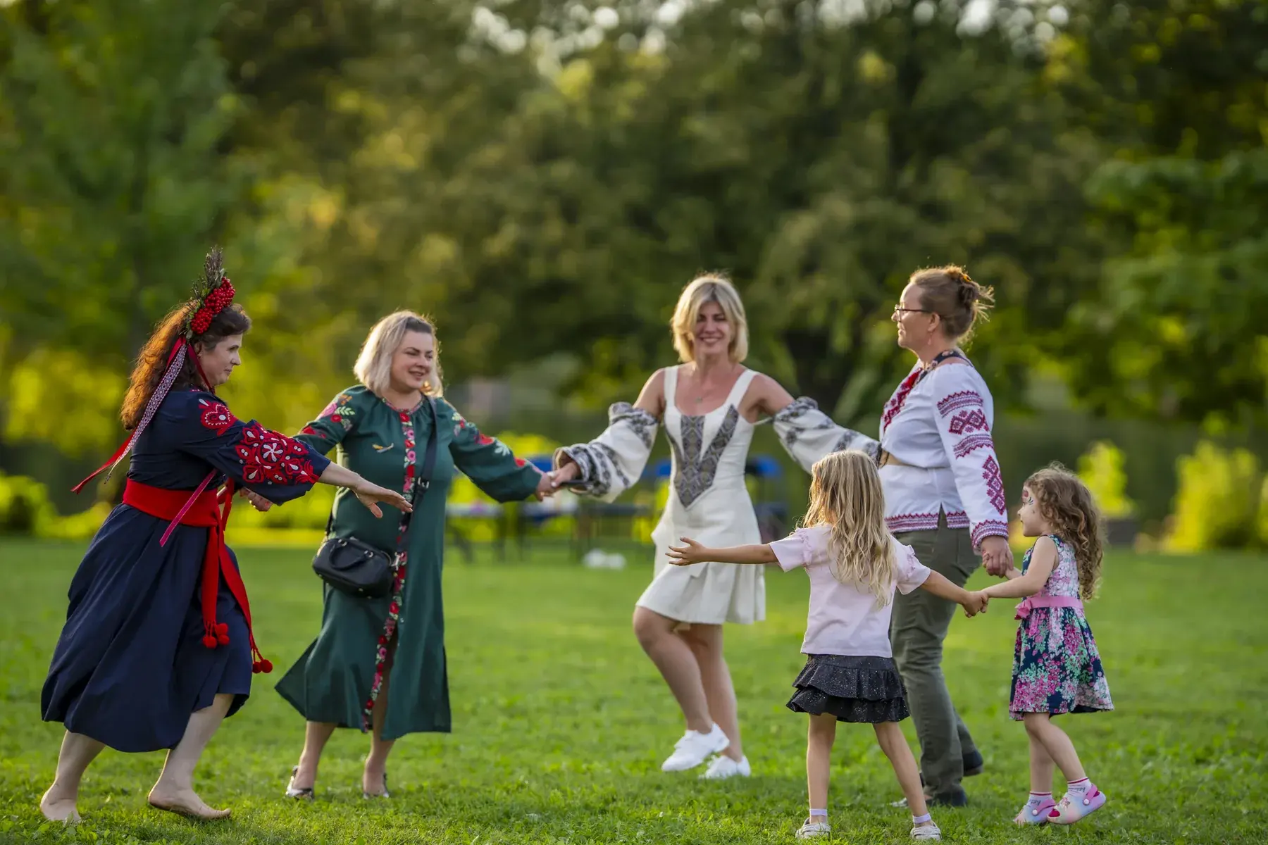 Women and little girls dancing in a circle on the grass